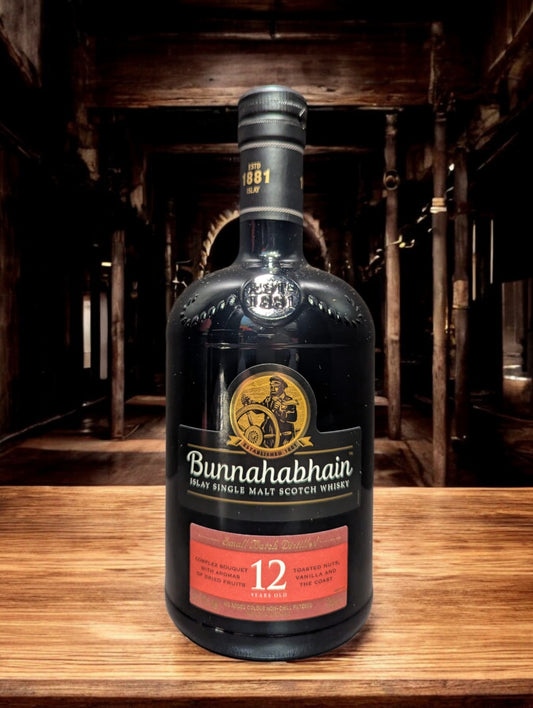 Flasche Bunnahabhain 12 Jahre Single Malt Scotch Whisky, präsentiert vor einem dunklen Hintergrund, die das sanfte Bernstein des Whiskys hervorhebt und das traditionelle, maritime Design des Etiketts mit den charakteristischen maritimen Elementen und der klaren Schrift akzentuiert.