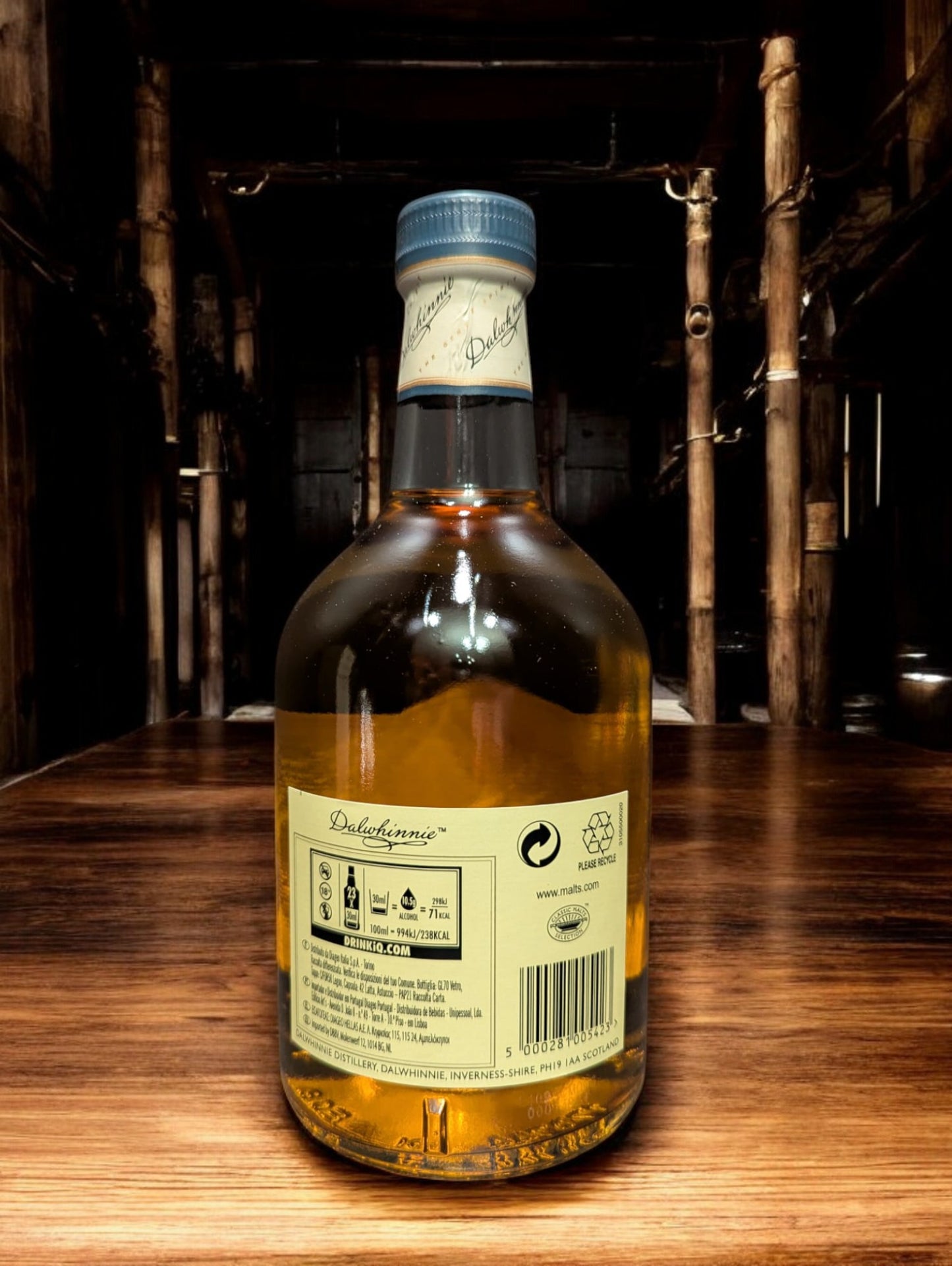 Eine Flasche Dalwhinnie 15 Jahre Single Malt Scotch Whisky steht aufrecht vor einem dunkelgrauen Hintergrund. Die elegante, klare Glasflasche zeigt ein cremefarbenes Etikett mit goldenen Akzenten und schwarzer Schrift. Der goldene Whisky schimmert im Licht und wird von einem markanten, kugelförmigen Flaschenhals mit einem schwarzen Verschluss gekrönt. Die gesamte Szene wirkt edel und zeitlos, was die hohe Qualität des Whiskys unterstreicht.