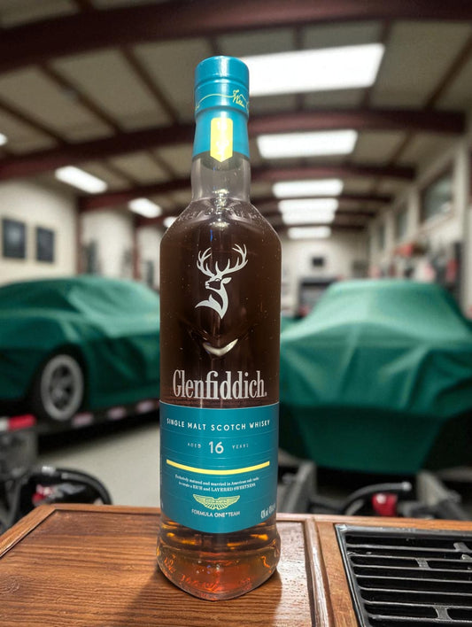 Flasche und Verpackung Glenfiddich 16 in einer Garage vor abgedecktem Aston Martin