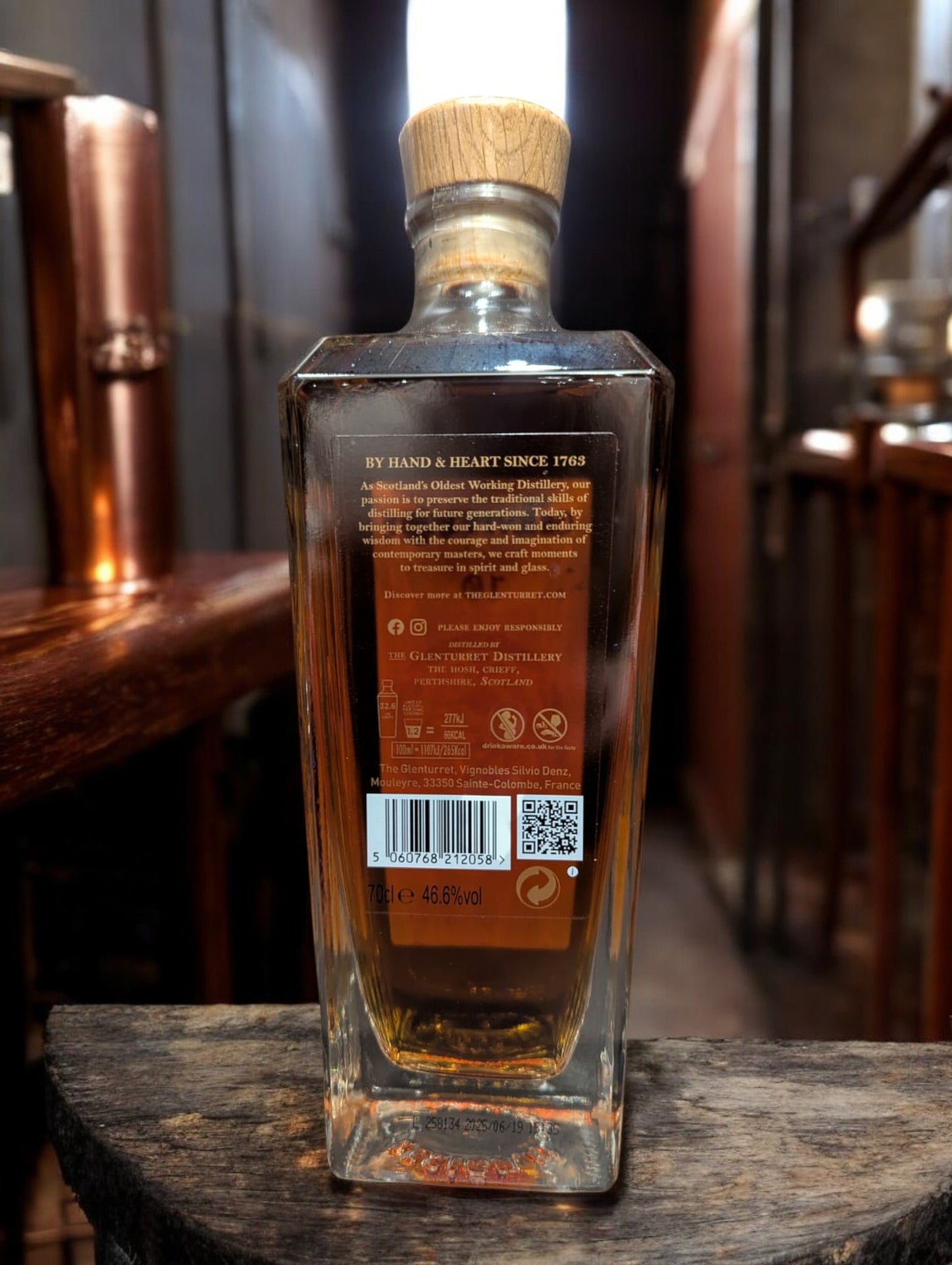 Glenturret 10 Jahre Peat Smoked Whisky vor dunklem Distillenhintergrund