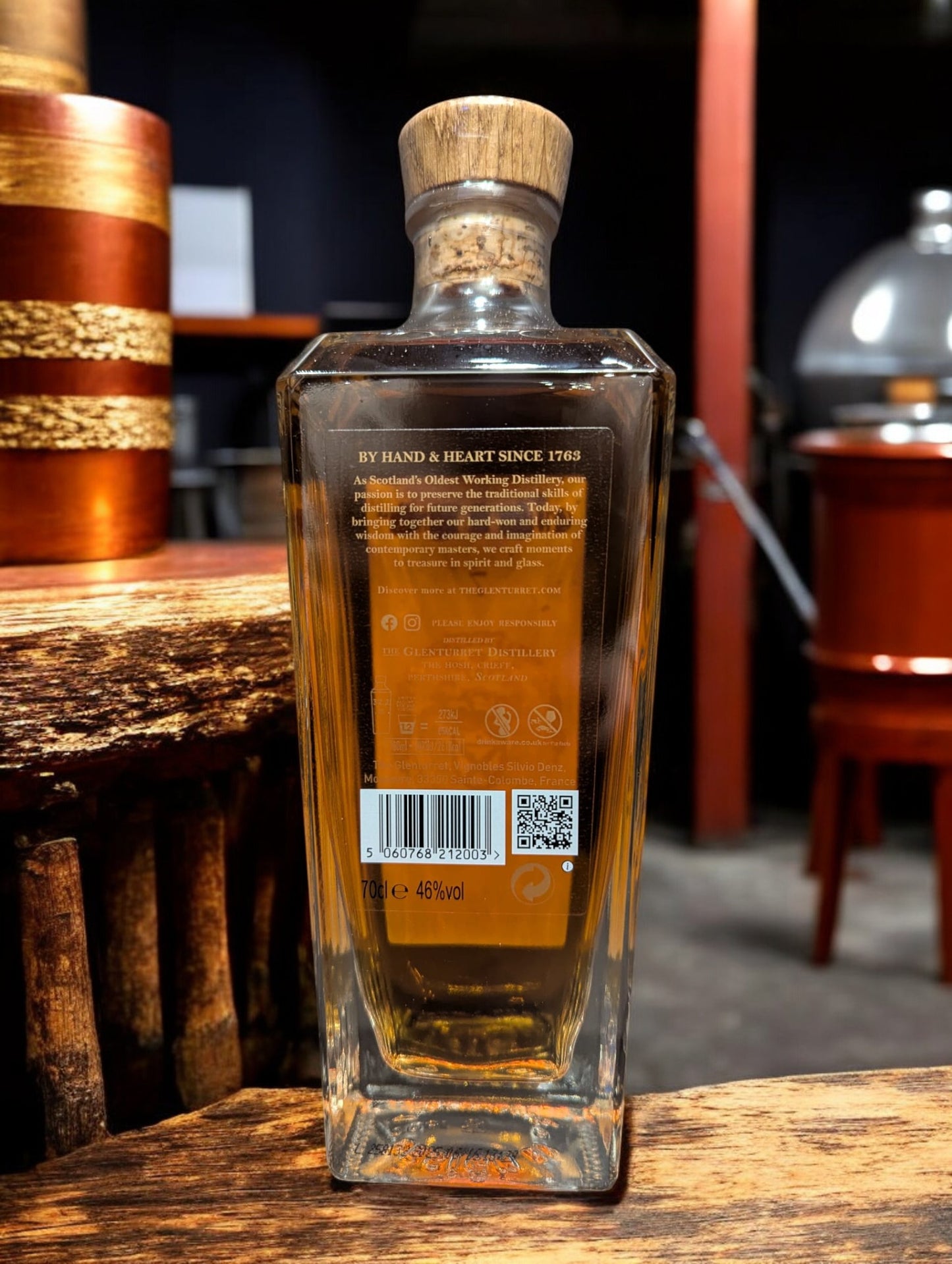 Flasche Glenturret Peat Smoked 7 Jahre Whisky vor dunklem, holzigem Hintergrund