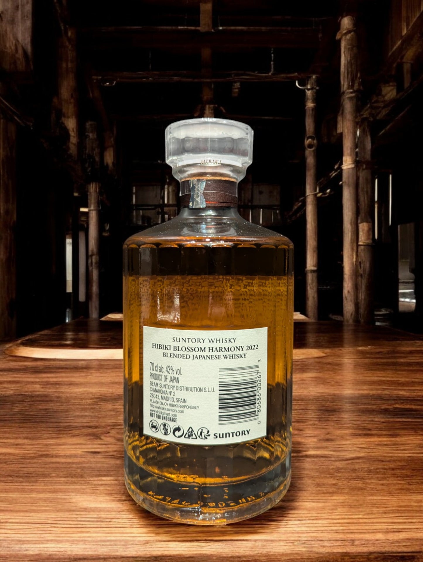 Flasche von Hibiki Blossom Harmony Whisky, umgeben von zarten Kirschblüten, auf einem eleganten dunklen Hintergrund, der die warmen Bernsteintöne des Getränks hervorhebt.