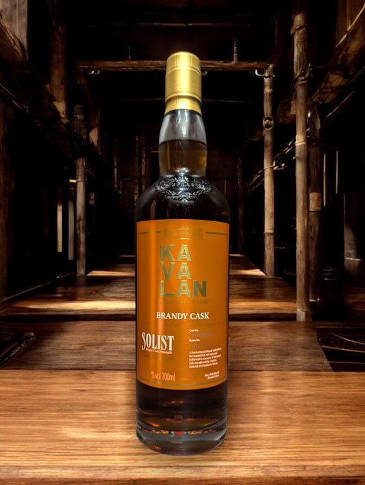 Flasche Kavalan Solist Brandy Single Malt Whisky vor einem dunkelgrauen Hintergrund, hervorgehoben durch sanfte Beleuchtung, die die elegante Form und das leuchtend goldene Label betont.