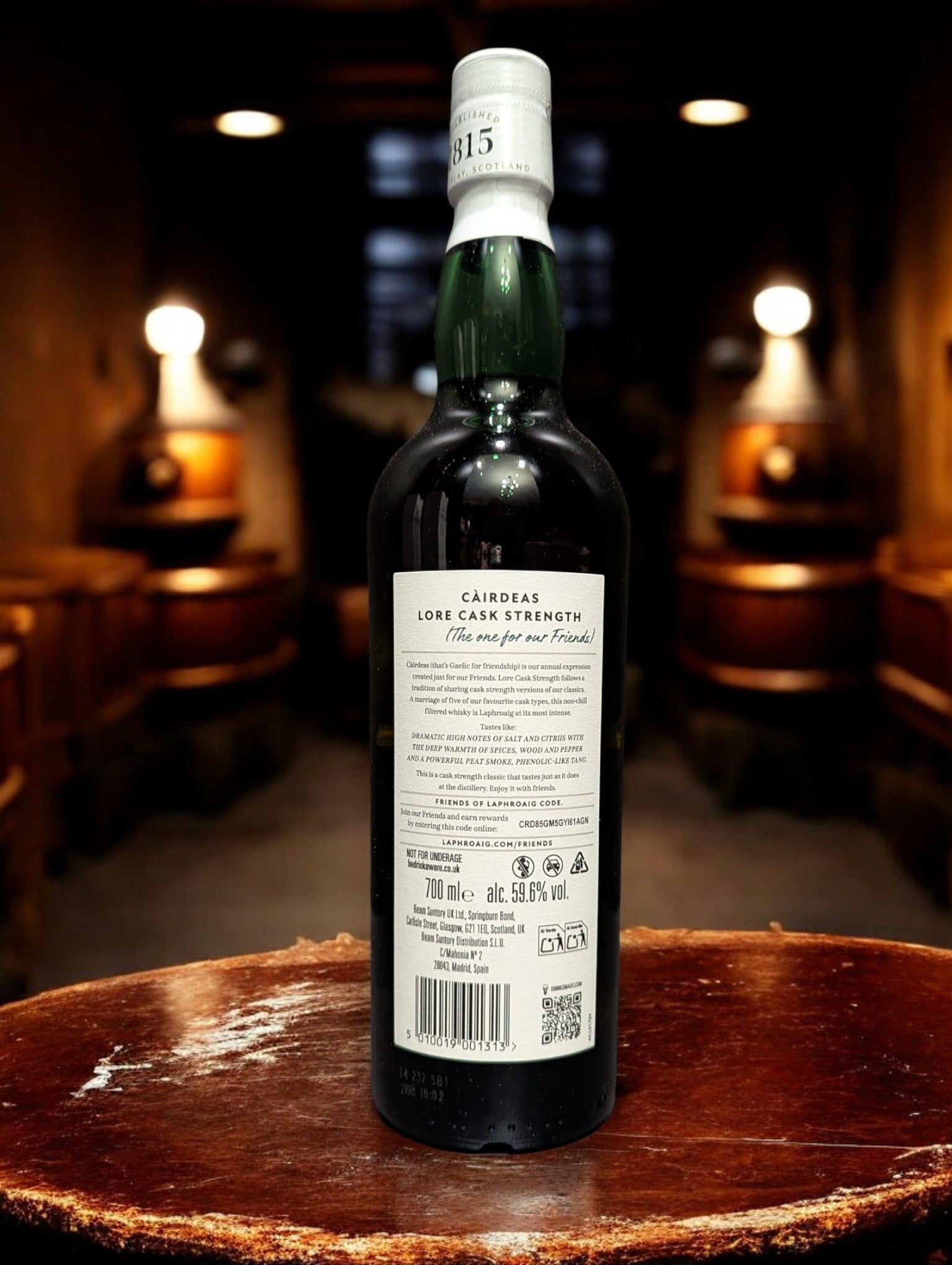 Eine Flasche Laphroaig Cairdeas 2025 Single Malt Whisky auf einem Holztisch vor dunklem Hintergrund