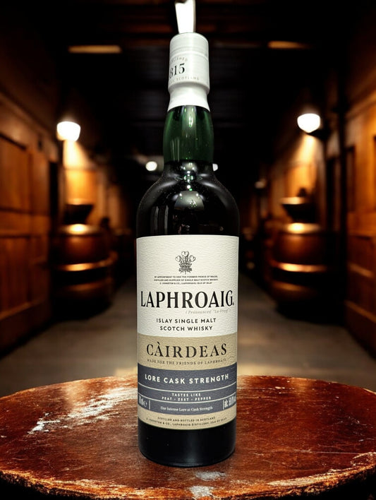 Eine Flasche Laphroaig Cairdeas 2025 Single Malt Whisky auf einem Holztisch vor dunklem Hintergrund