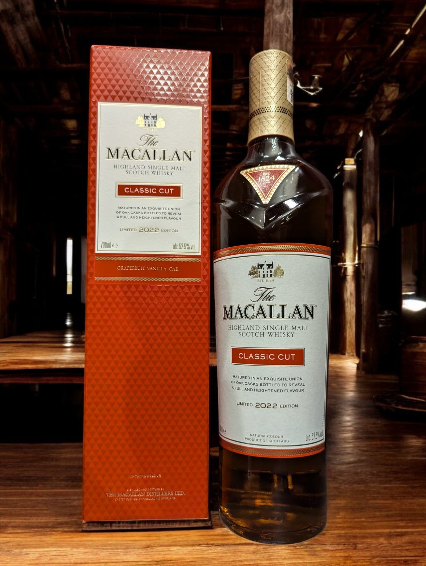 Präsentation der Macallan Classic Cut 2022 Flasche mit ausgeprägter, satter Bernsteinfarbe des Whiskys, betont durch ein anspruchsvolles Etikettendesign, vor einem Hintergrund, der die Exklusivität und handwerkliche Qualität dieser jährlichen limitierten Edition unterstreicht.
