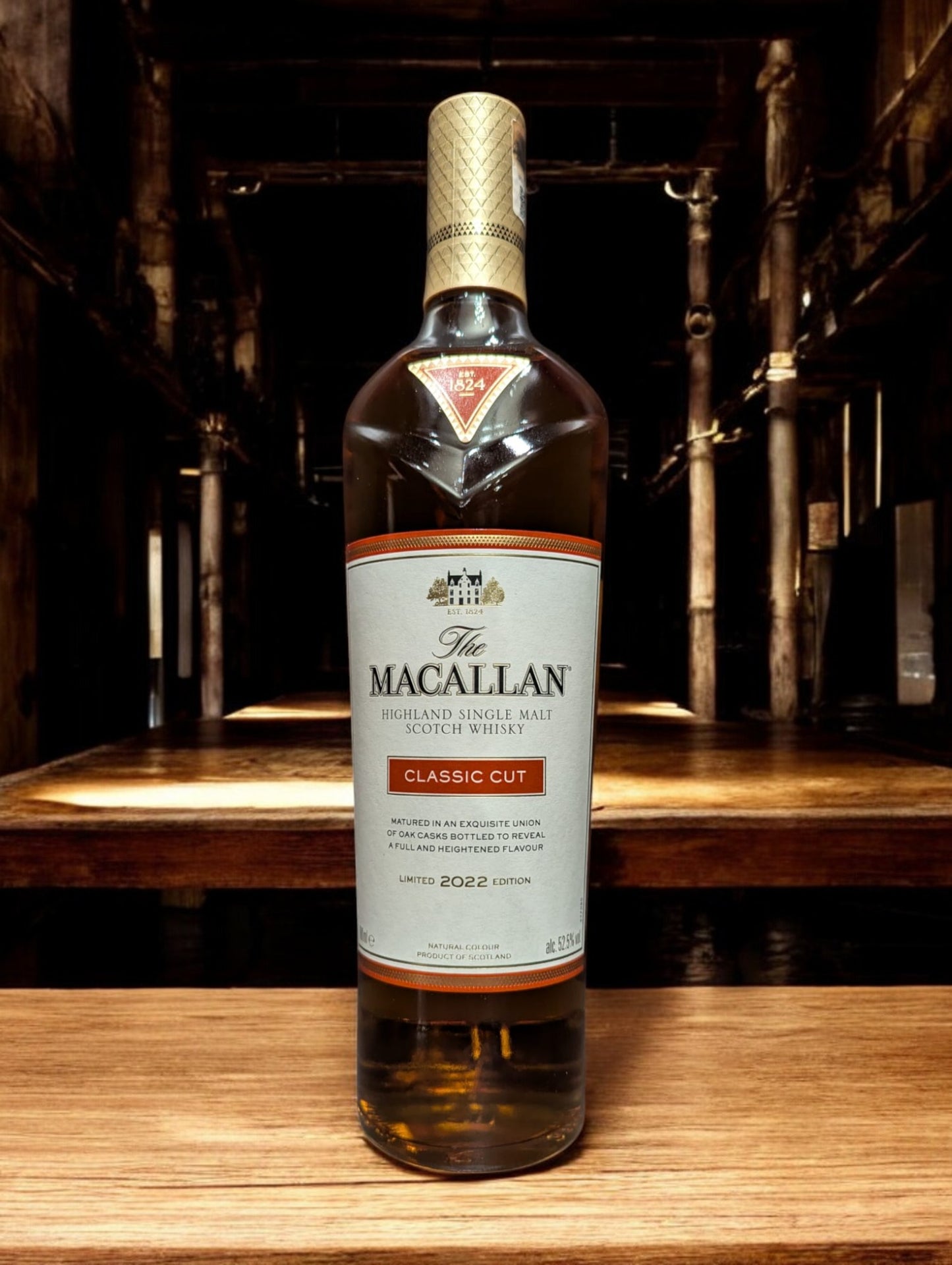 Präsentation der Macallan Classic Cut 2022 Flasche mit ausgeprägter, satter Bernsteinfarbe des Whiskys, betont durch ein anspruchsvolles Etikettendesign, vor einem Hintergrund, der die Exklusivität und handwerkliche Qualität dieser jährlichen limitierten Edition unterstreicht.