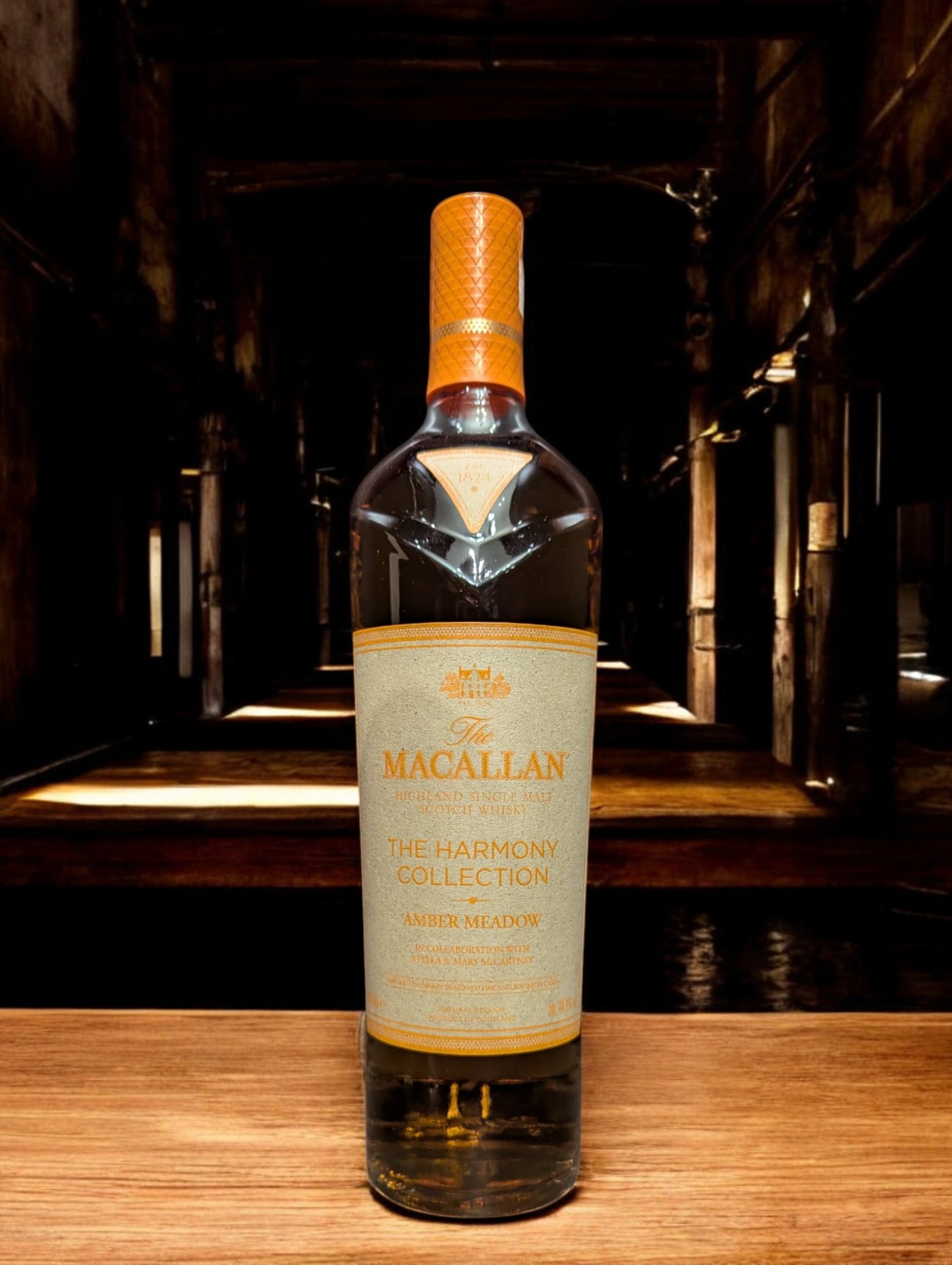 Flasche Macallan Harmony Collection Amber Meadow Whisky, elegant platziert vor einem dunkelgrauen Hintergrund, mit einem sanften Licht, das die reiche, honiggoldene Farbe des Whiskys und die raffinierten Details auf dem Etikett hervorhebt.