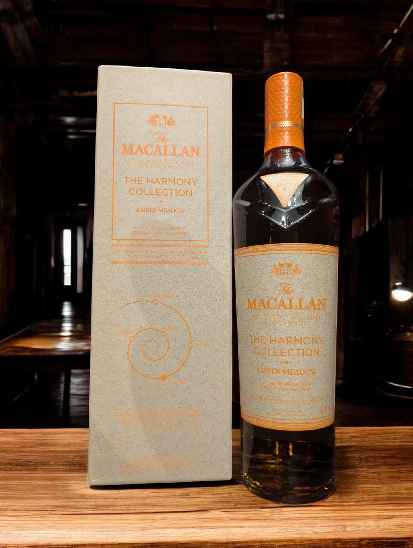 Flasche Macallan Harmony Collection Amber Meadow Whisky, elegant platziert vor einem dunkelgrauen Hintergrund, mit einem sanften Licht, das die reiche, honiggoldene Farbe des Whiskys und die raffinierten Details auf dem Etikett hervorhebt.