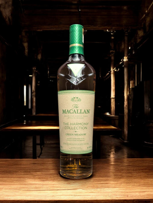 Flasche Macallan Harmony Collection Green Meadow Single Malt Whisky vor einem dunkelgrauen Hintergrund, mit einem subtilen Schimmer, der die grünlichen Akzente auf der Flasche und das hochwertige Etikett akzentuiert.