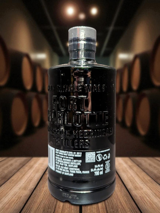 Eine Flasche Port Charlotte Whisky, vor dunklem Hintergrund mit Fässern