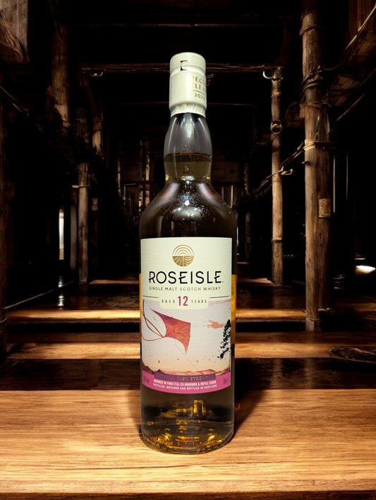 Flasche Roseisle 12 Jahre Single Malt Whisky steht im Vordergrund, scharf fokussiert, mit einem unscharfen industriellen Hintergrund aus Edelstahltanks und Rohrleitungen, die an einen modernen Brennereibetrieb erinnern.