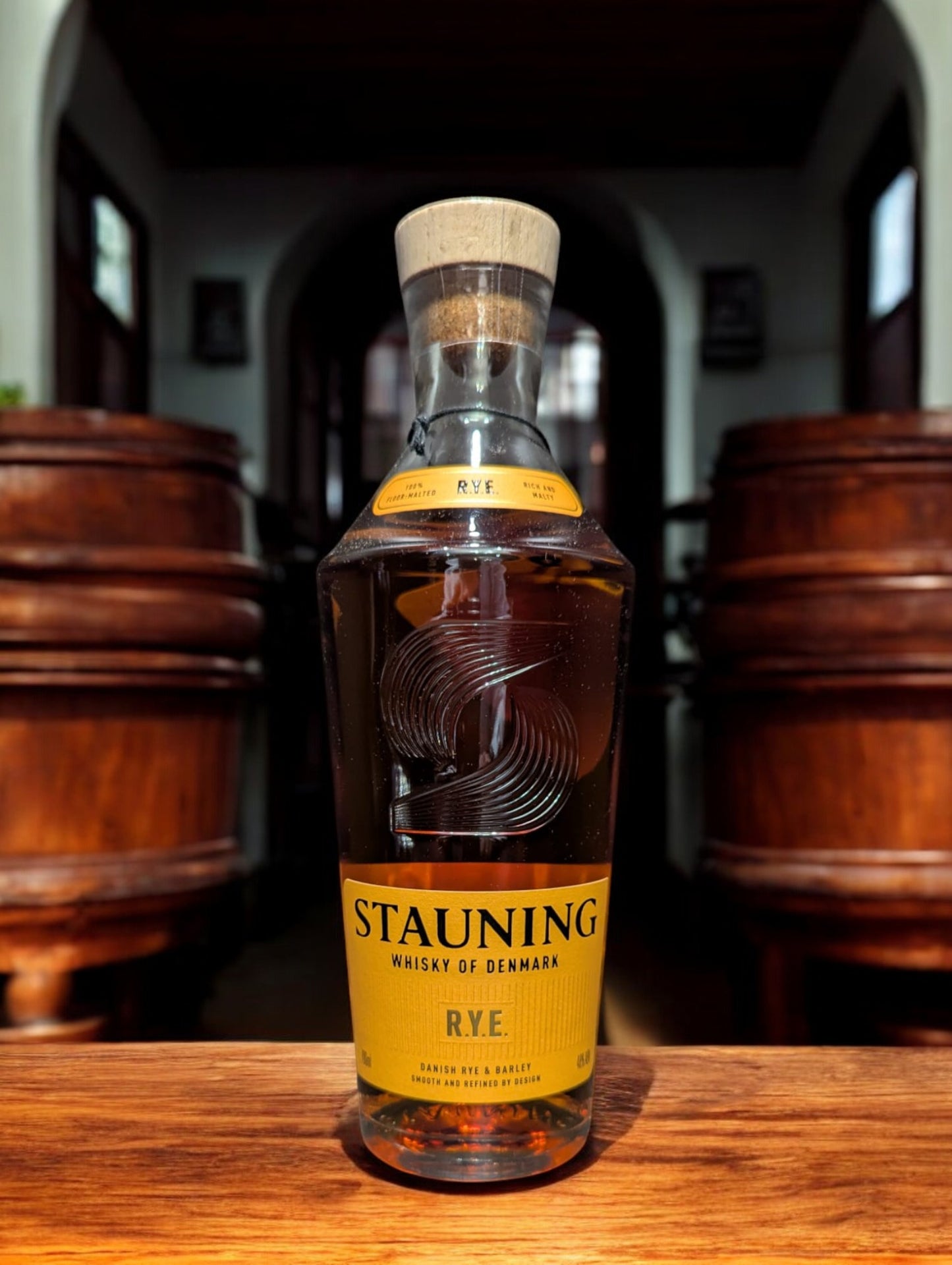 Flasche Stauning Rye auf einem Tisch vor Fässern