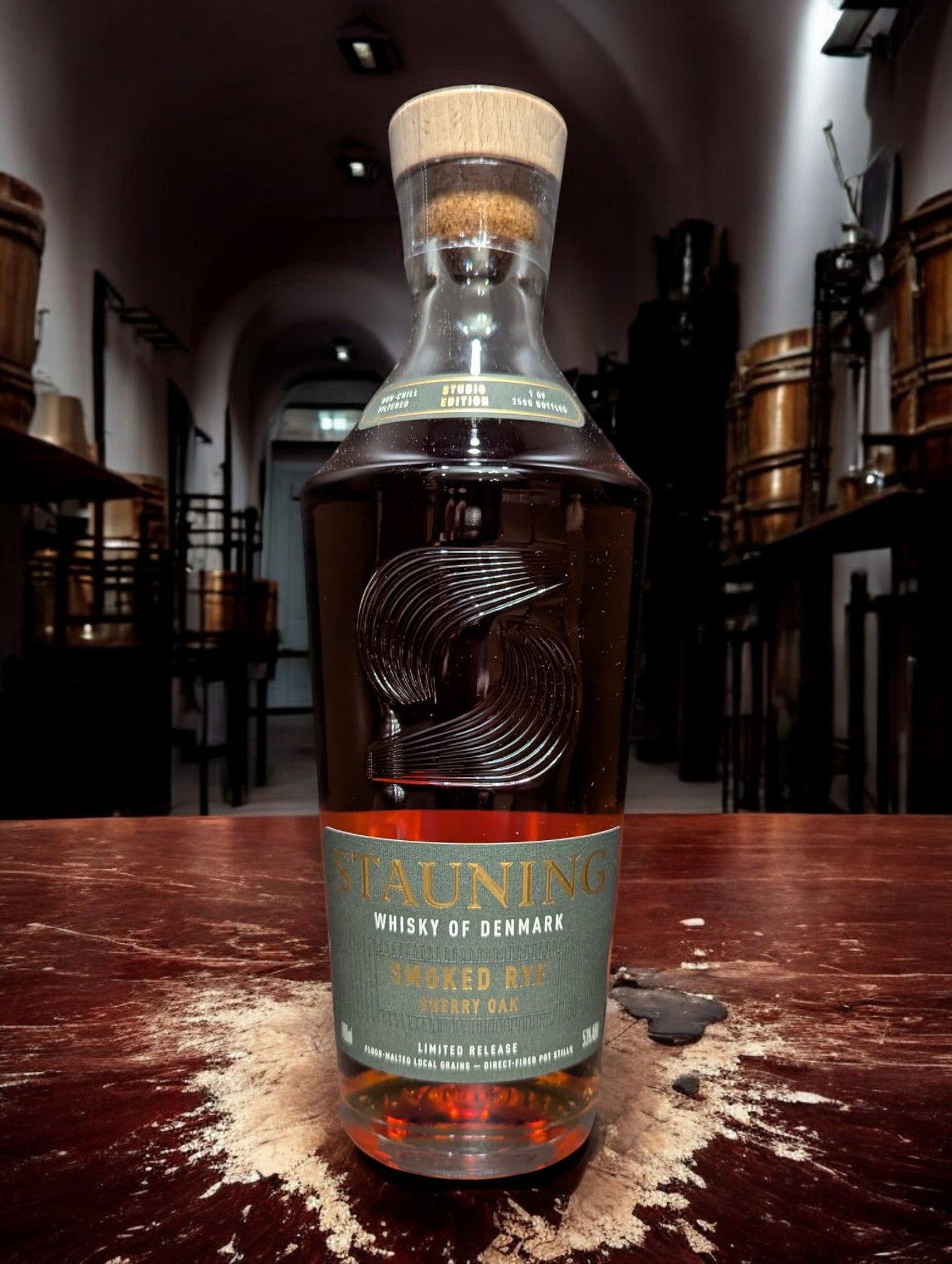 Stauning Smoked Rye - Danish Studio Edition Whisky auf einem Tisch vor dunklem Hintergrund einer Distille