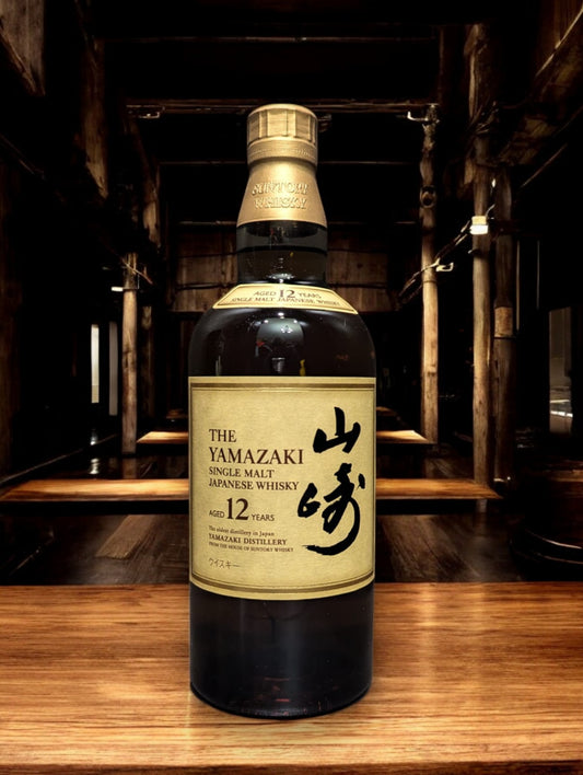 Detailaufnahme der Suntory Yamazaki Whiskyflasche, umgeben von Eichenfässern im Lagerhaus. Das warme Licht unterstreicht die goldbraune Farbe des edlen Single Malt Whiskys. Der Name Yamazaki prangt stolz auf dem Etikett, was auf die traditionsreiche Whiskybrennerei in Japan hinweist. Die Szene vermittelt eine Atmosphäre von Qualität und Handwerkskunst, die in der Herstellung dieses renommierten Getränks steckt.