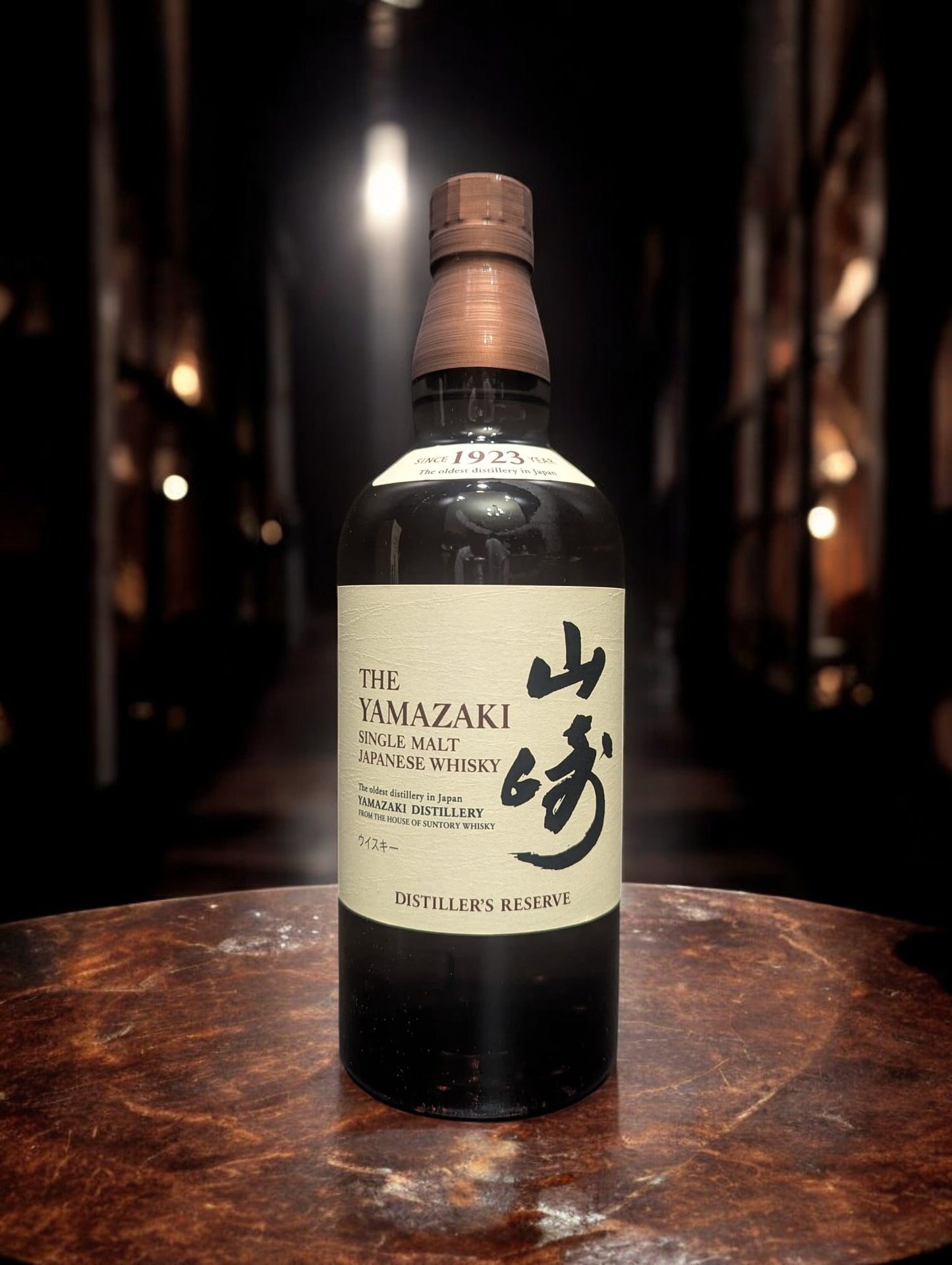 Eine Flasche Yamazaki Distiller Reserve vor dunklem Hintergrund mit Distillenequipment für Whisky