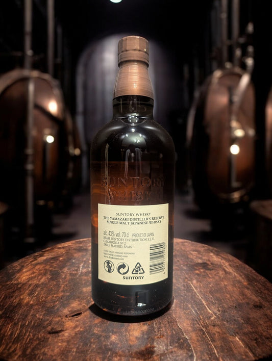 Eine Flasche Yamazaki Distiller Reserve vor dunklem Hintergrund mit Distillenequipment für Whisky