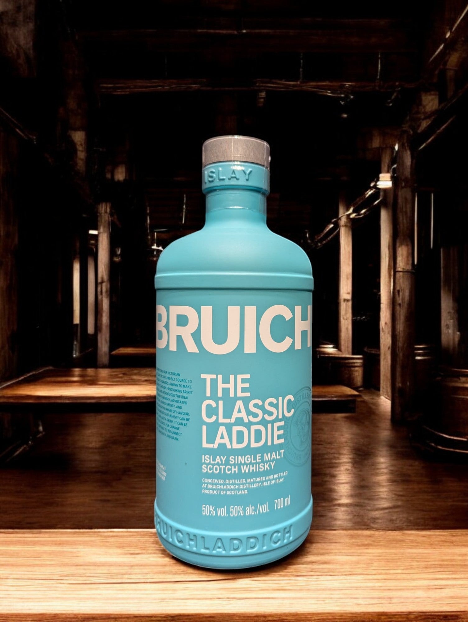 
Ein Bruichladdich Classic Laddie Whisky in einer Destilleriehalle, umgeben von warmen Holzelementen, Kupferbrennblasen und Holzfässern. Die markante türkisfarbene Flasche hebt sich von der rustikalen Umgebung ab, die eine gemütliche und traditionelle Atmosphäre ausstrahlt.