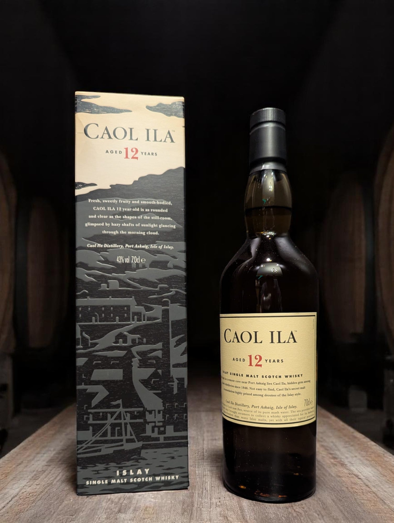 Flasche Caol Ila 12 Years Single Malt Whisky vor dunkler Destillerie-Kulisse.