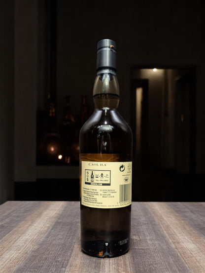 Flasche Caol Ila 12 Years Single Malt Whisky vor dunkler Destillerie-Kulisse.