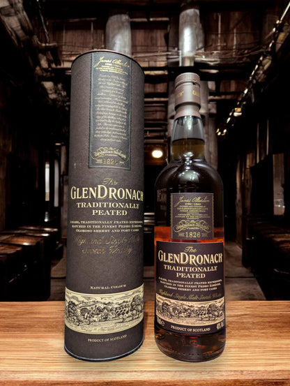 Eine Flasche Glendronach Traditionally Peated Whisky in einer stimmungsvollen Destilleriehalle, umgeben von massiven Holzfässern und alten Steinmauern. Die dunkle, edle Flasche mit goldenen Akzenten steht im Kontrast zur rustikalen Umgebung und vermittelt einen Hauch von traditionellem Handwerk und Whiskygeschichte.