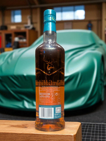 Flasche und Verpackung Glenfiddich 16 in einer Garage vor abgedecktem Aston Martin