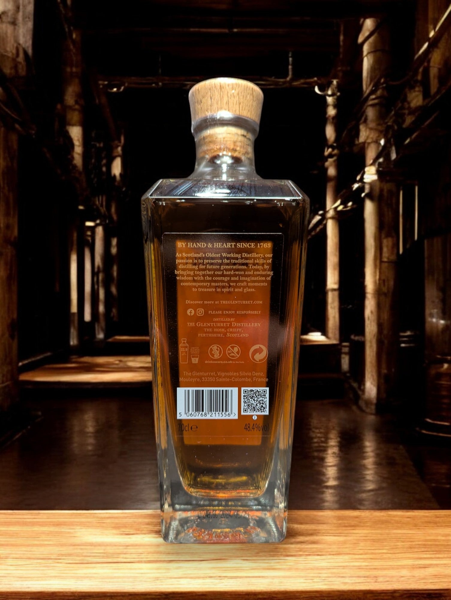 Flasche Glenturret 10 yo Peat Smoked Whisky vor dunklem, industriellem Hintergrund, betonend die rauchige Eleganz des Malts.