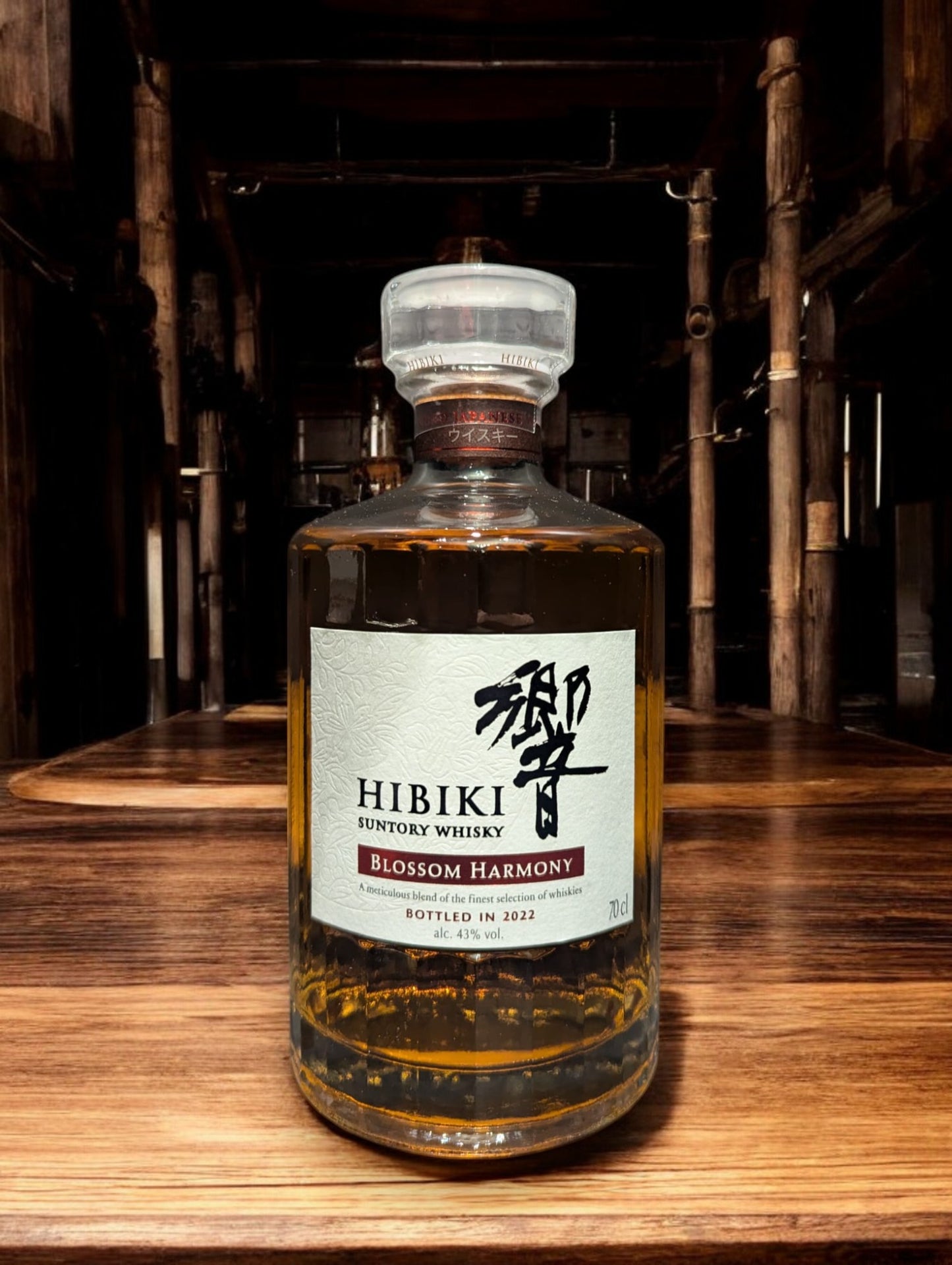 Flasche von Hibiki Blossom Harmony Whisky, umgeben von zarten Kirschblüten, auf einem eleganten dunklen Hintergrund, der die warmen Bernsteintöne des Getränks hervorhebt.