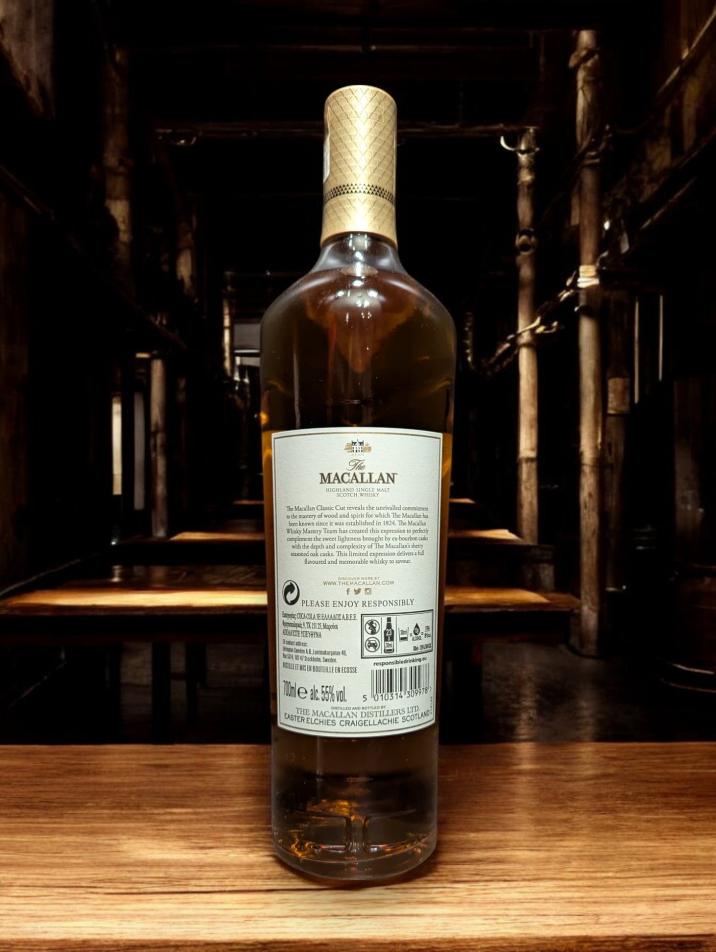 Edle, klar geformte Flasche Macallan Classic Cut 2020 Single Malt Scotch Whisky mit goldener Typografie auf schwarzem Etikett, neben einem Glas, das die goldene Farbe des Whiskys zeigt, auf einem Hintergrund, der Eleganz und Qualität ausstrahlt.