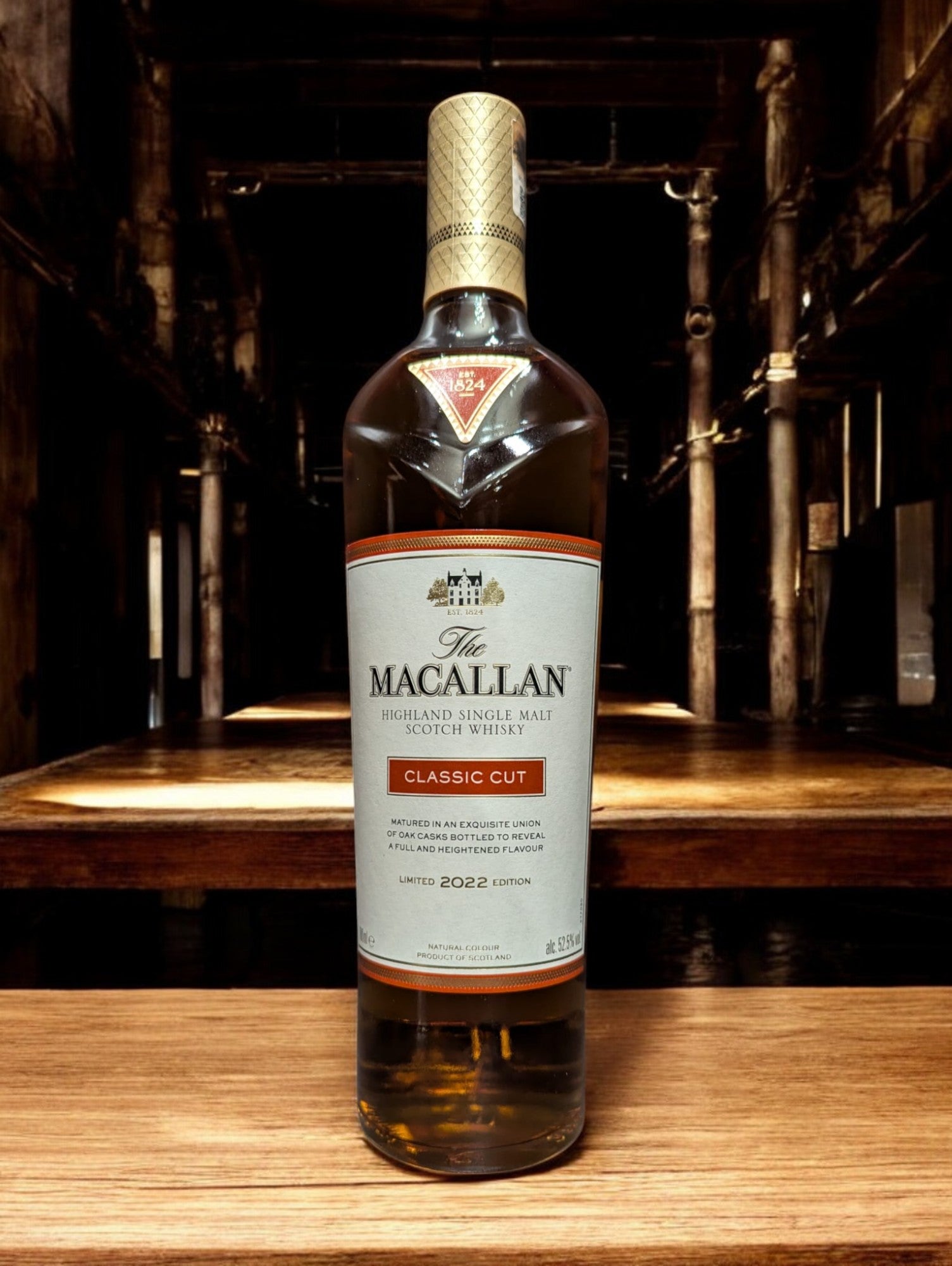 Präsentation der Macallan Classic Cut 2022 Flasche mit ausgeprägter, satter Bernsteinfarbe des Whiskys, betont durch ein anspruchsvolles Etikettendesign, vor einem Hintergrund, der die Exklusivität und handwerkliche Qualität dieser jährlichen limitierten Edition unterstreicht.