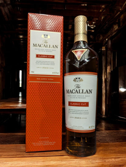 Die Flasche Macallan Classic Cut 2023 steht im Vordergrund, ihr reicher, leuchtend goldener Whisky lädt zu einer multisensorischen Geschmacksreise ein. Das Design des Etiketts strahlt Exklusivität aus und deutet auf die komplexe Aromenvielfalt hin, die Kenner bei der Verkostung erwarten können, eingebettet in einen anspruchsvollen und luxuriösen Kontext.