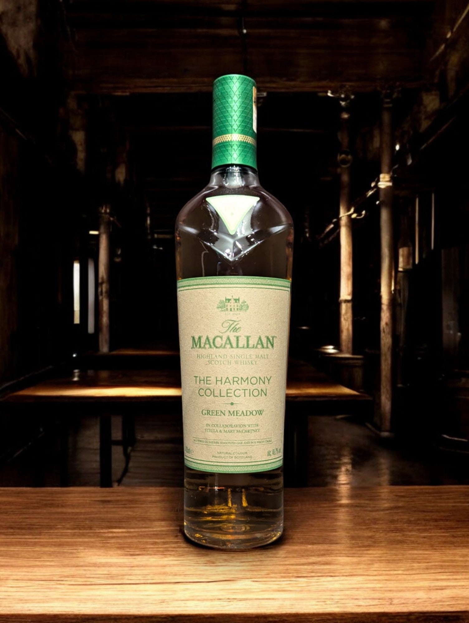 Flasche Macallan Harmony Collection Green Meadow Single Malt Whisky vor einem dunkelgrauen Hintergrund, mit einem subtilen Schimmer, der die grünlichen Akzente auf der Flasche und das hochwertige Etikett akzentuiert.