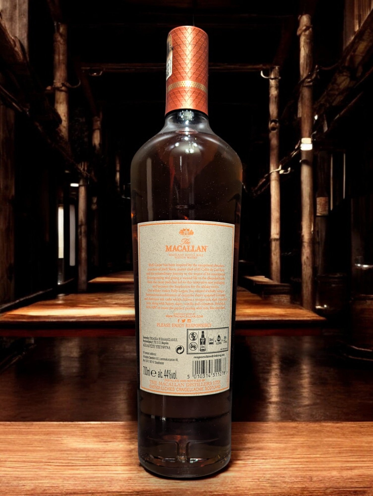 Flasche Macallan Harmony Collection Rich Cacao Whisky, präsentiert vor einem dunklen Hintergrund, mit einem dezenten Glanz, der die luxuriöse, dunkelbraune Farbgebung des Whiskys und das stilvolle, schokoladenfarbene Etikett unterstreicht.
