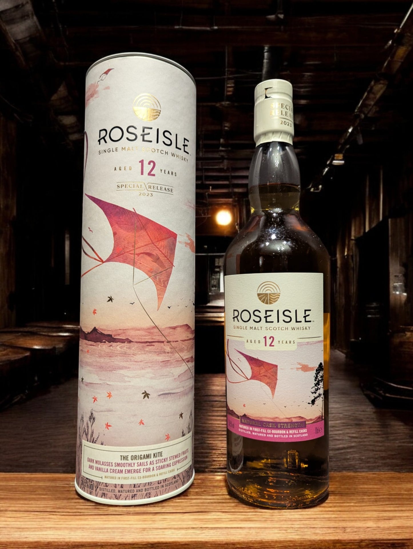 Flasche Roseisle 12 Jahre Single Malt Whisky steht im Vordergrund, scharf fokussiert, mit einem unscharfen industriellen Hintergrund aus Edelstahltanks und Rohrleitungen, die an einen modernen Brennereibetrieb erinnern.