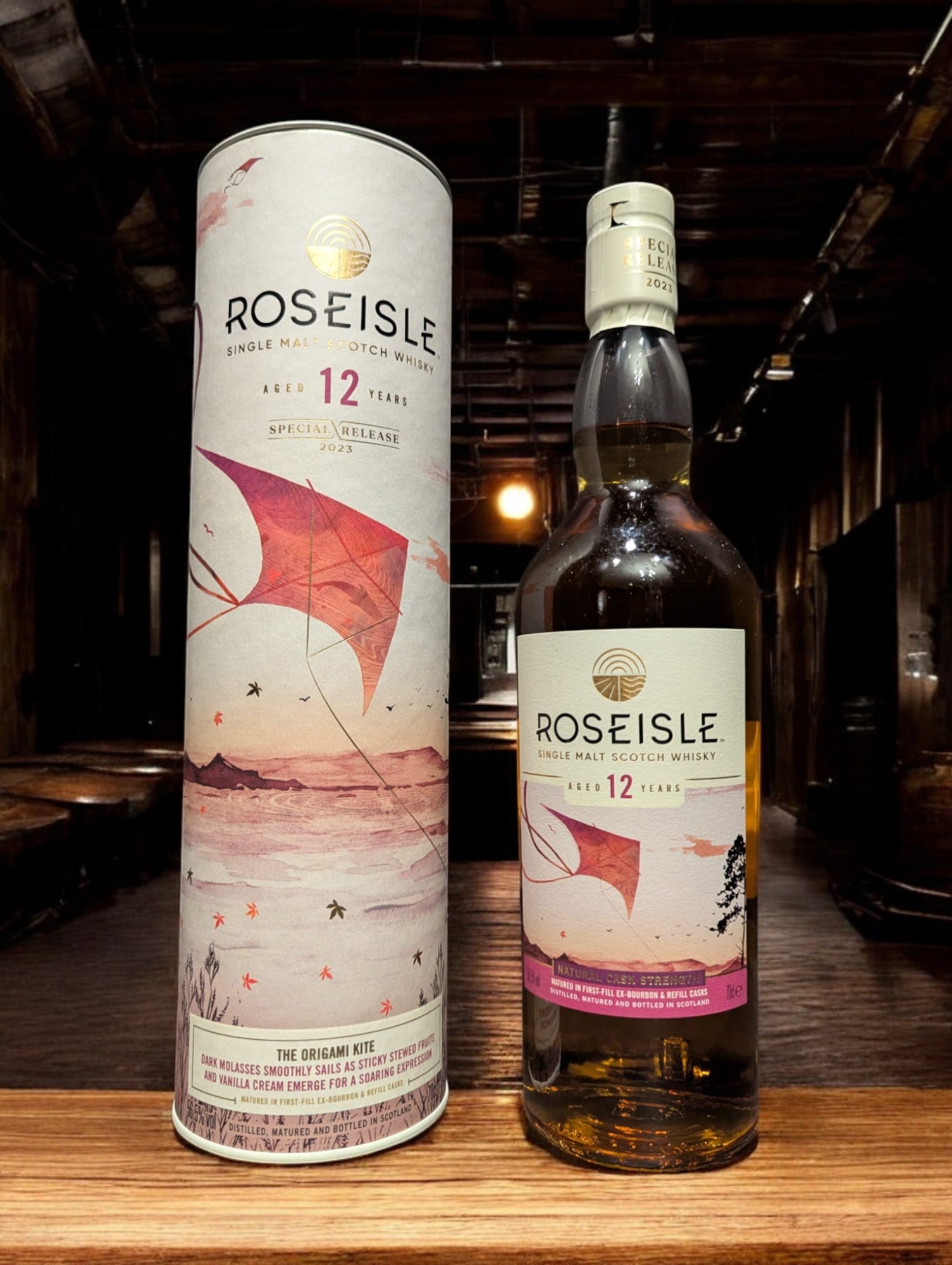 Flasche Roseisle 12 Jahre Single Malt Whisky steht im Vordergrund, scharf fokussiert, mit einem unscharfen industriellen Hintergrund aus Edelstahltanks und Rohrleitungen, die an einen modernen Brennereibetrieb erinnern.