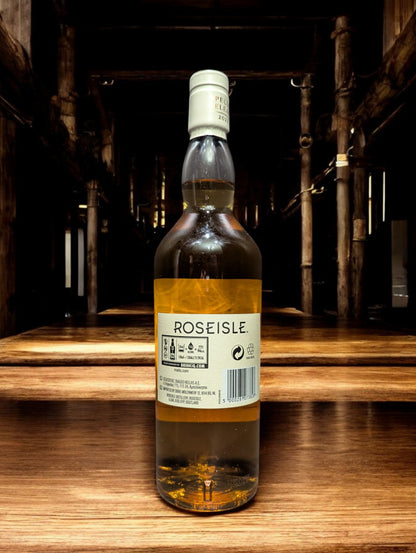 Flasche Roseisle 12 Jahre Single Malt Whisky steht im Vordergrund, scharf fokussiert, mit einem unscharfen industriellen Hintergrund aus Edelstahltanks und Rohrleitungen, die an einen modernen Brennereibetrieb erinnern.