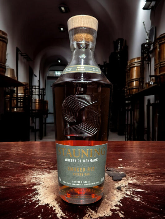 Stauning Smoked Rye - Danish Studio Edition Whisky auf einem Tisch vor dunklem Hintergrund einer Distille