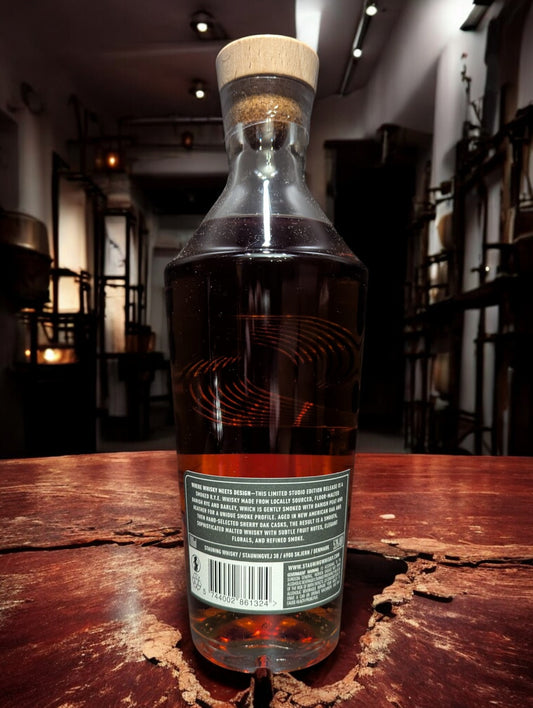Stauning Smoked Rye - Danish Studio Edition Whisky auf einem Tisch vor dunklem Hintergrund einer Distille