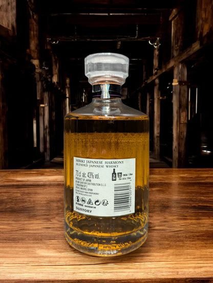 Flasche Suntory Hibiki Harmony Whisky vor einem dunkelgrauen Hintergrund, wobei das edle Design der Flasche mit ihrer facettenreichen Glasstruktur und das elegante Etikett mit goldener Schrift durch den Kontrast hervorgehoben werden und der goldene Farbton des Whiskys sanft durchscheint.