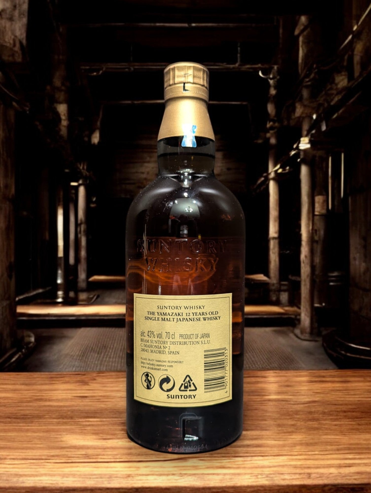 Detailaufnahme der Suntory Yamazaki Whiskyflasche, umgeben von Eichenfässern im Lagerhaus. Das warme Licht unterstreicht die goldbraune Farbe des edlen Single Malt Whiskys. Der Name Yamazaki prangt stolz auf dem Etikett, was auf die traditionsreiche Whiskybrennerei in Japan hinweist. Die Szene vermittelt eine Atmosphäre von Qualität und Handwerkskunst, die in der Herstellung dieses renommierten Getränks steckt.