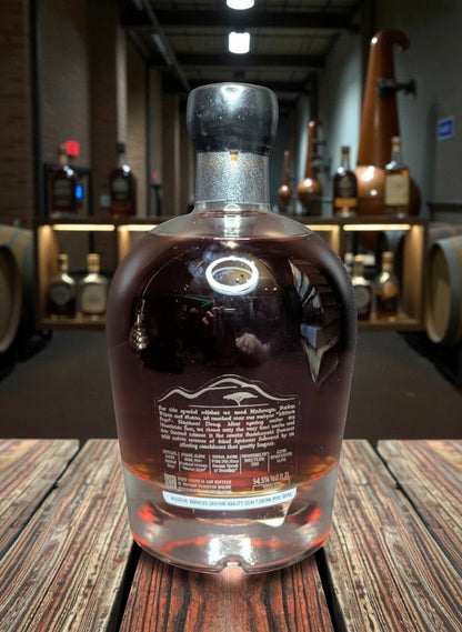 Whiskyquartier Ondjaba Signature Edition #1 Namibian Single Malt 0.7L Flasche mit bernsteinfarbener Flüssigkeit, vor einem Hintergrund von Destillierapparaten und Fässern.