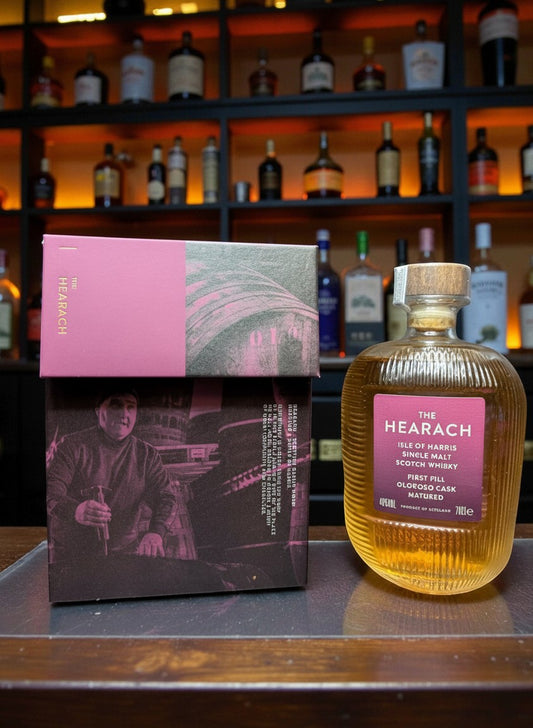 The Hearach Oloroso Sherry Release Single Malt Scotch Whisky 0.7L in einer gerippten Flasche mit rosa Etikett. Neben der Flasche liegt die passende Geschenkbox.