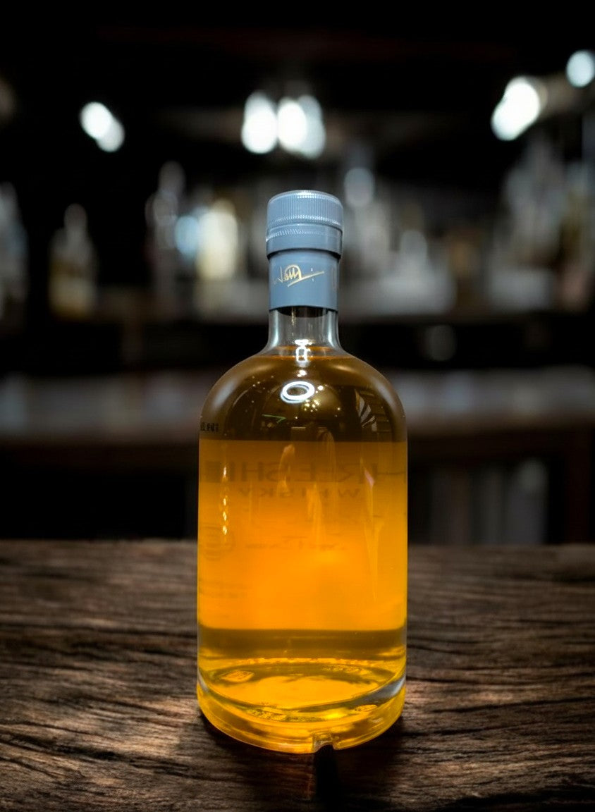 Whiskyquartier: Three Ships 12 YO Master Distiller Collection Single Malt Whisky in bernsteinfarbener Flüssigkeit in Glasflasche mit grauem Verschluss.